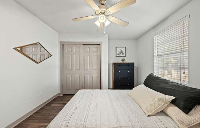 A bedroom with a bed, dresser, and ceiling fan.