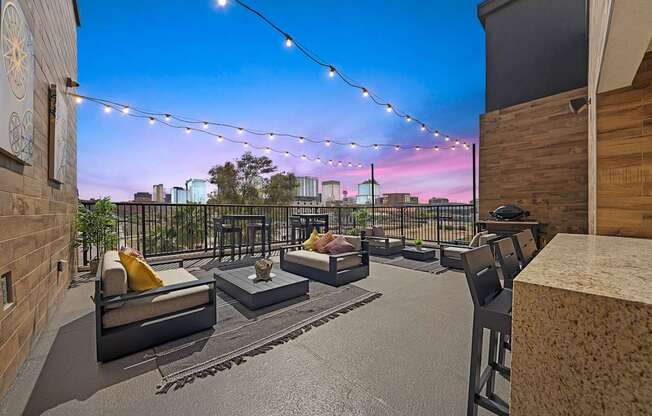 A balcony with a couch, coffee table, and string lights.