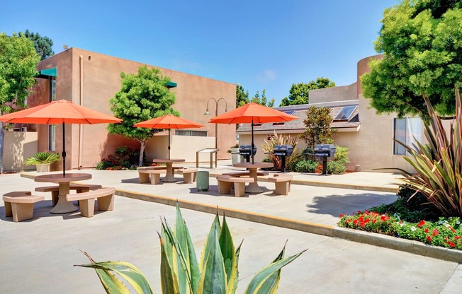 A sunny day at the outdoor seating area of a restaurant with orange umbrellas and benches.