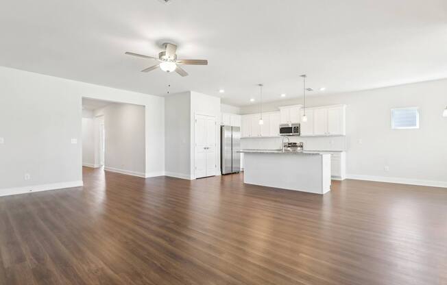 A spacious room with wooden floors and a ceiling fan.