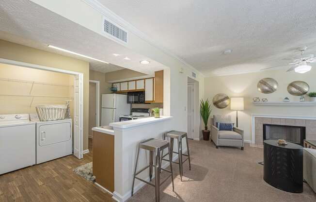 a living room with a kitchen and a bar with stools