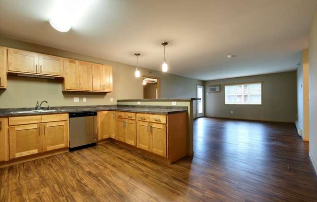 an empty kitchen and living room with wood floors and wood cabinets. Fargo, ND Urban Plains Apartments