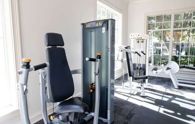 A gym with a black chair and a black and silver machine.