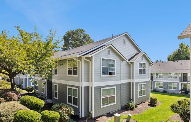 A grey house with a white roof and a green lawn in front.