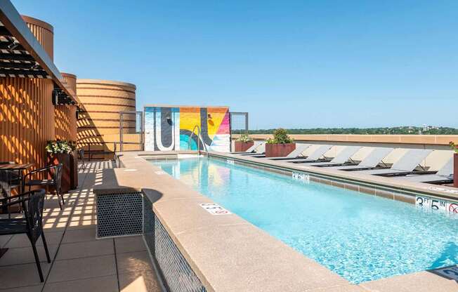 a swimming pool on the rooftop of a hotel with chairs around it