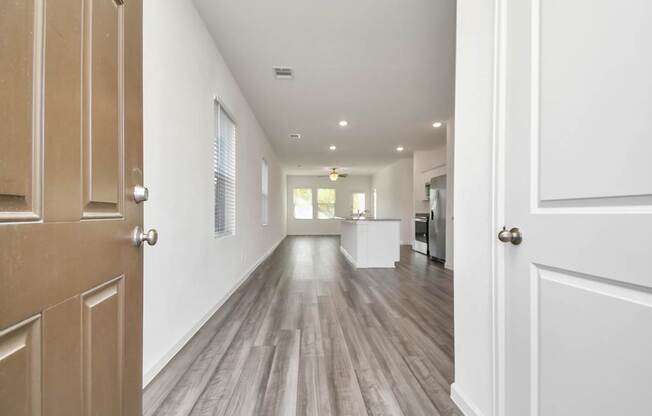 A long hallway with wood floors and white walls.