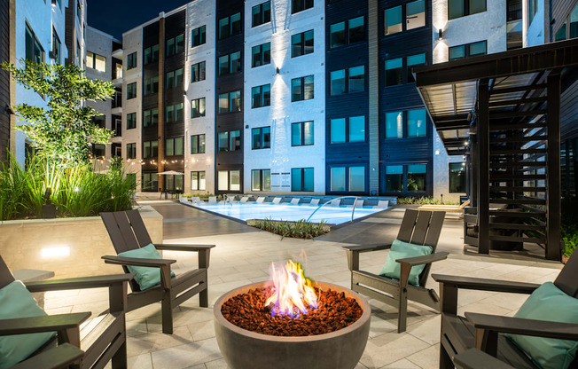A fire pit sits in the middle of a patio surrounded by chairs.