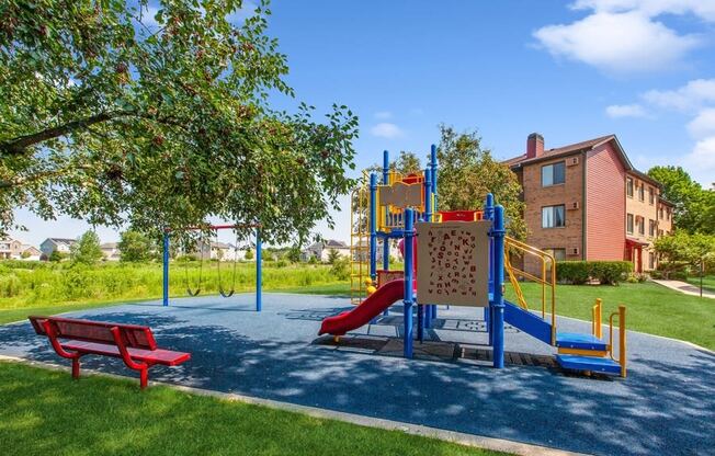 a playground with a red bench and a building in the background