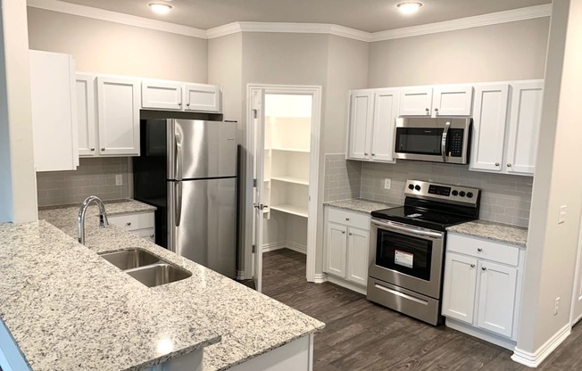 a kitchen with white cabinets and a granite counter top