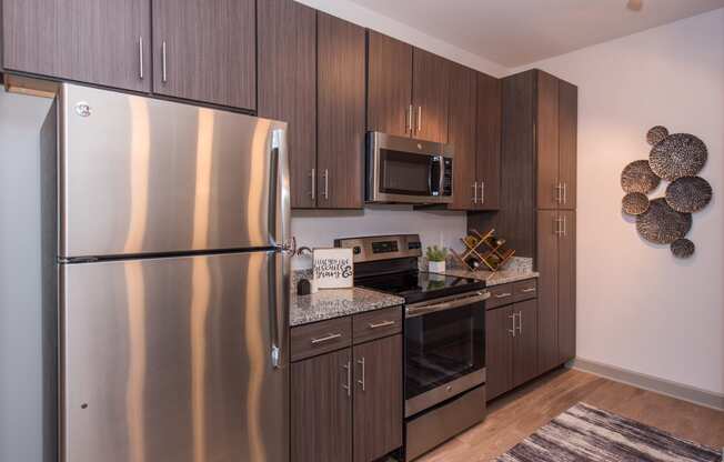 a kitchen with dark wood cabinets and stainless steel appliances at The Whitworth, Virginia, 23185