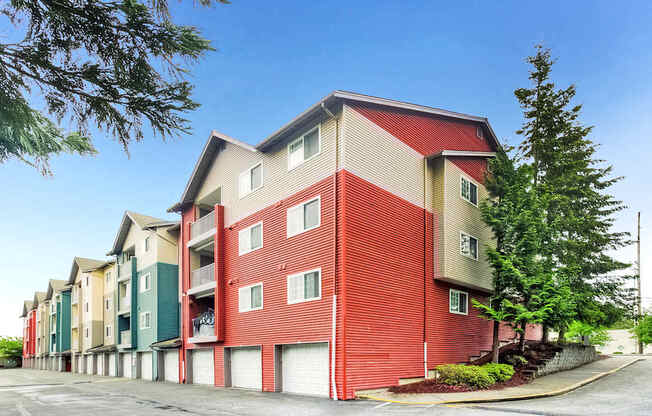 A red and beige apartment building with a parking lot in front.