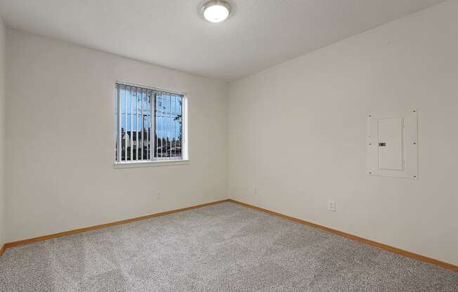 a bedroom with white walls and a window