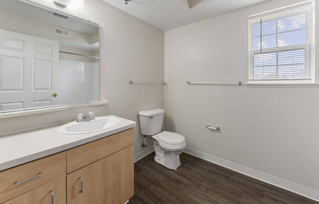 A bathroom with a window, toilet, sink, and mirror at Fieldstream Apartment Homes in IA 50023