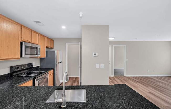 A kitchen with a black granite countertop and wooden cabinets.