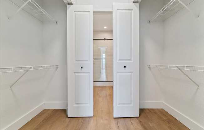 an empty closet with white doors and white walls and wood floors