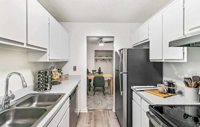 A kitchen with white cabinets and a black refrigerator.