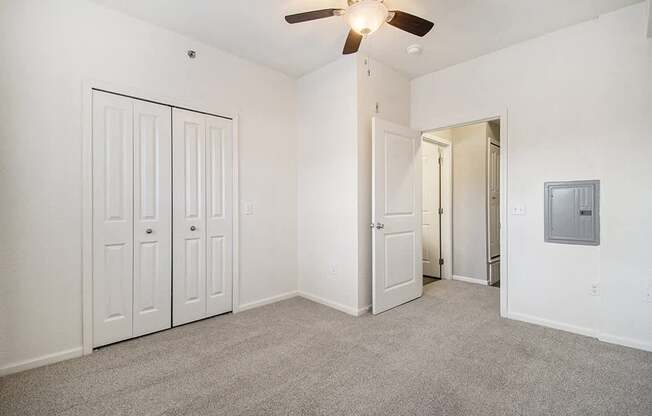 A spacious bedroom with a ceiling fan and a large closet at Lynbrook Apartments and Townhomes, Elkhorn, NE, 68022