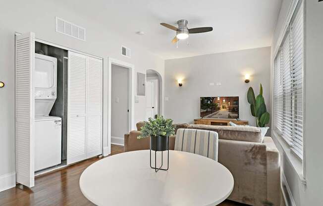 A white dining table with a plant on it in the middle of a room.