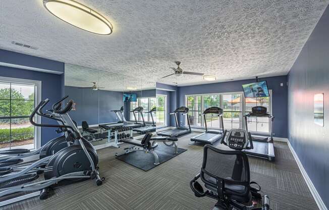 a gym with treadmills and other exercise equipment and windows