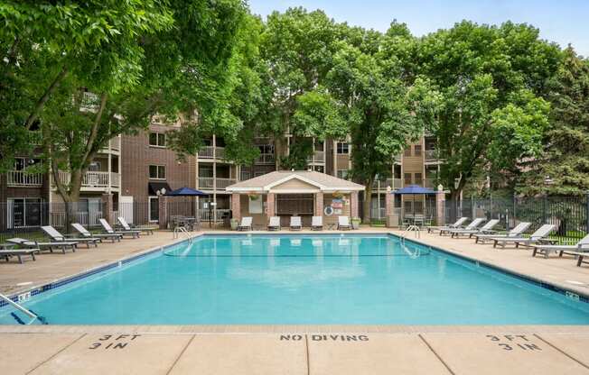 a resort style pool with lounge chairs and a building in the background