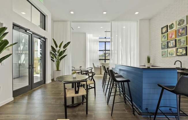 A modern kitchen with a blue counter and black chairs.