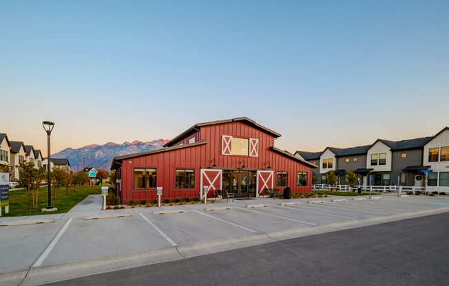 a red barn with a parking lot in front of some houses