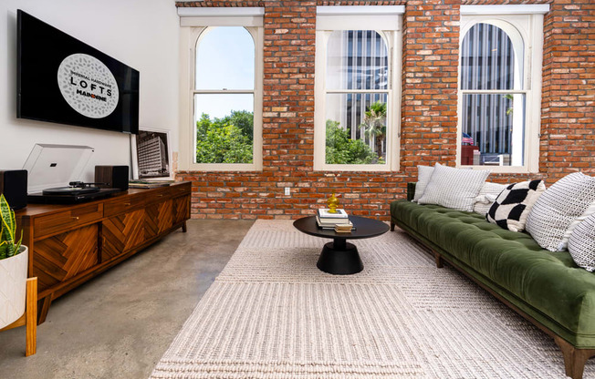 a living room with a green couch and a brick wall