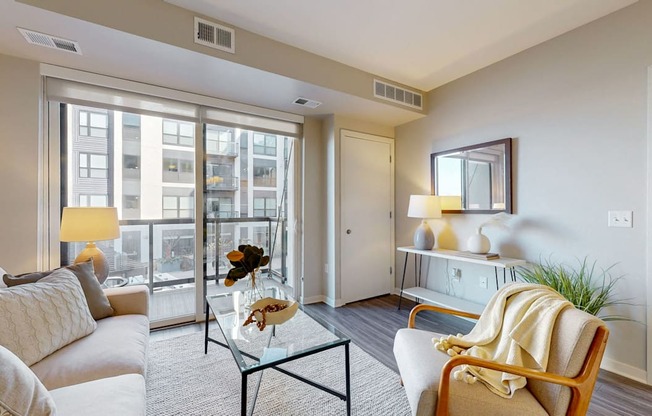 A living room with a white sofa, a glass coffee table, and a large window.