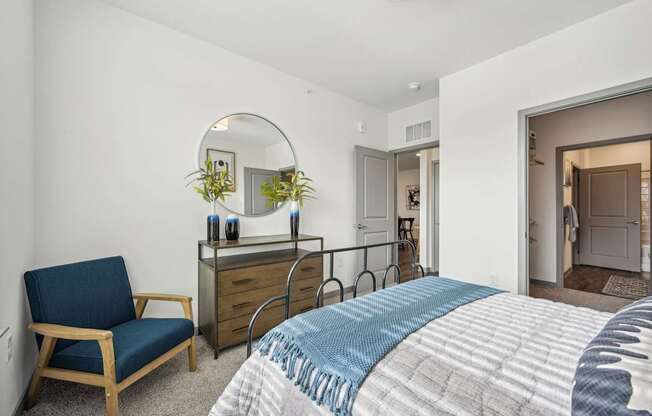 a bedroom with a bed and a dresser and a mirror at The Quarry Luxury Apartment Homes, Fort Collins, CO