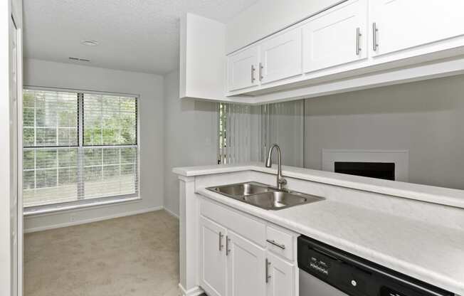 a kitchen with white cabinets and a large window at Canopy at Baybrook apartments in Charlotte NC