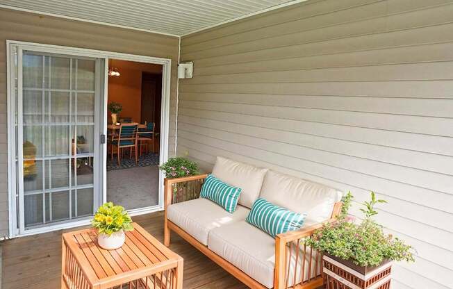 A white couch with blue pillows sits on a wooden deck.