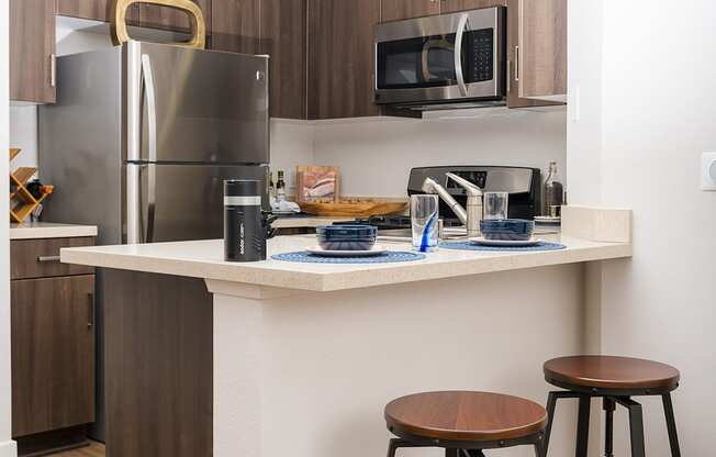 a kitchen with a counter and stools and a stainless steel refrigerator