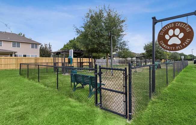 A sign for a community pet park is displayed on a fence.