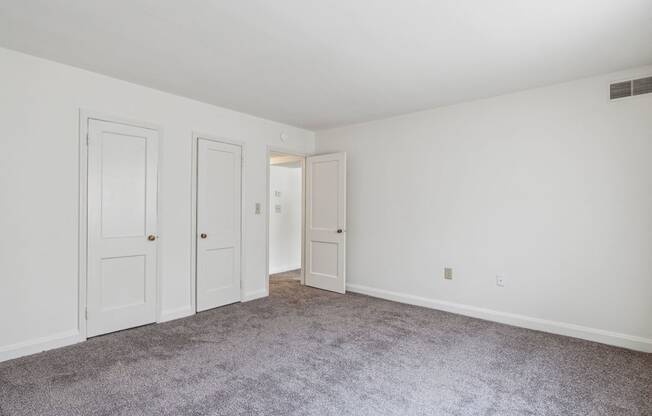 a bedroom with white walls and carpet and two doors