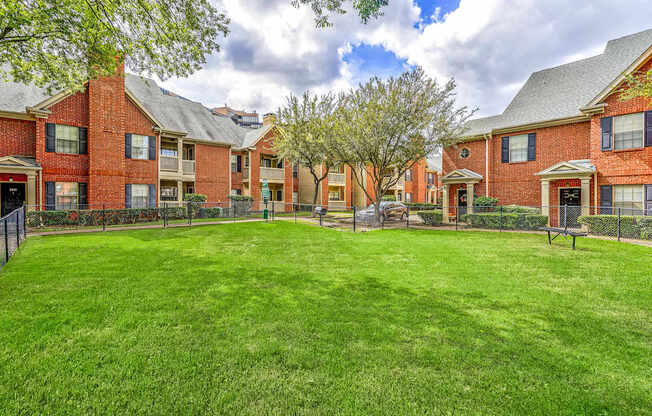 A large grassy area in front of a row of red brick houses.