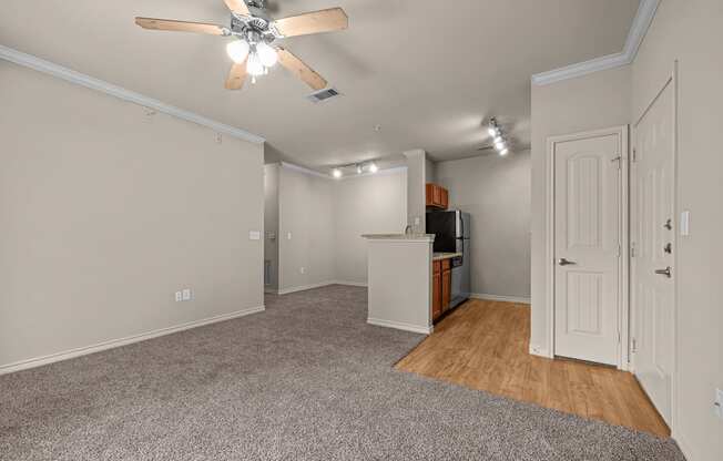 A room with a ceiling fan and a kitchenette.