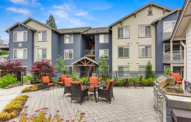 Community outdoor lounge area with chairs and cushions and the BBQ area is located in the same area.   