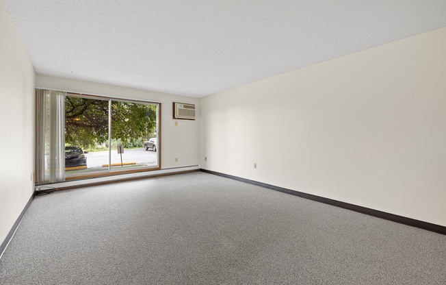 A room with a grey carpet and a white wall.