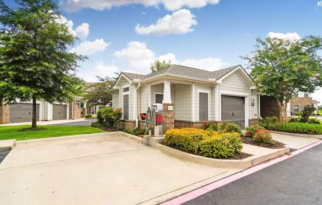 a white house with a driveway and a street with trees