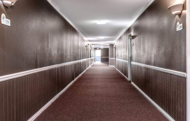 a hallway with wood paneled walls and a red carpet