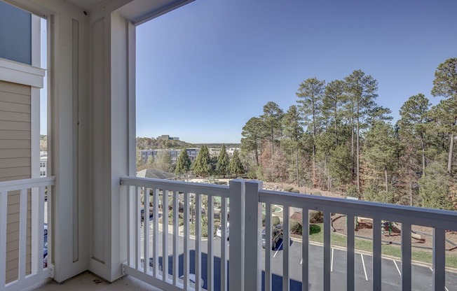 A balcony with a view of a parking lot and trees.