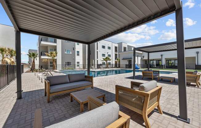 a patio with a pool and lounge chairs and tables