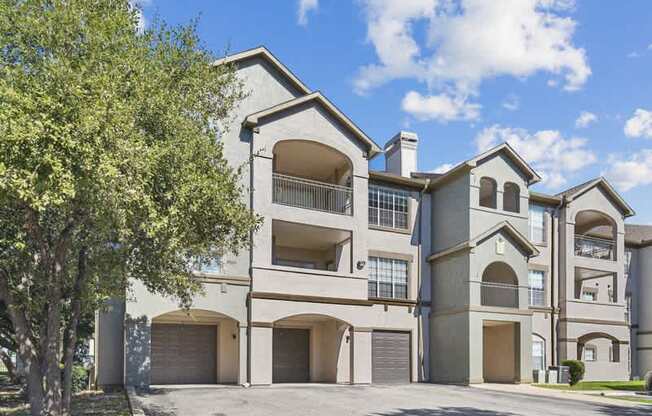 an apartment building with two garages and a tree