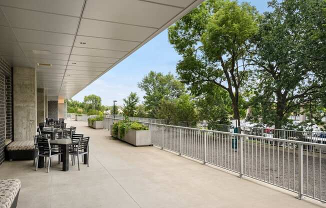 the terrace of the building has tables and chairs and a fence