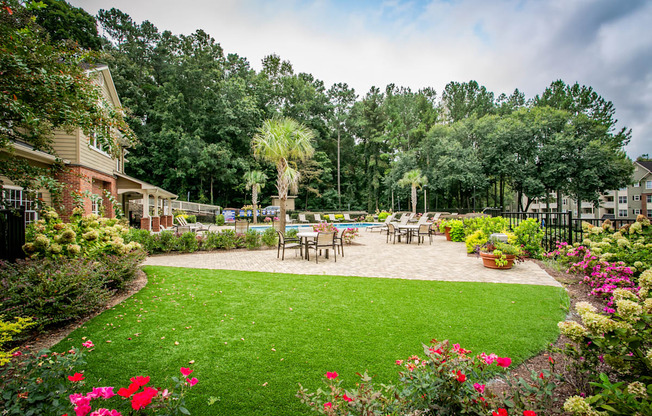 a backyard with a patio and a lawn with tables and chairs