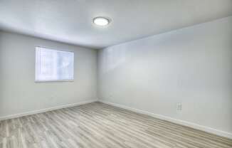 an empty room with wood flooring and a window