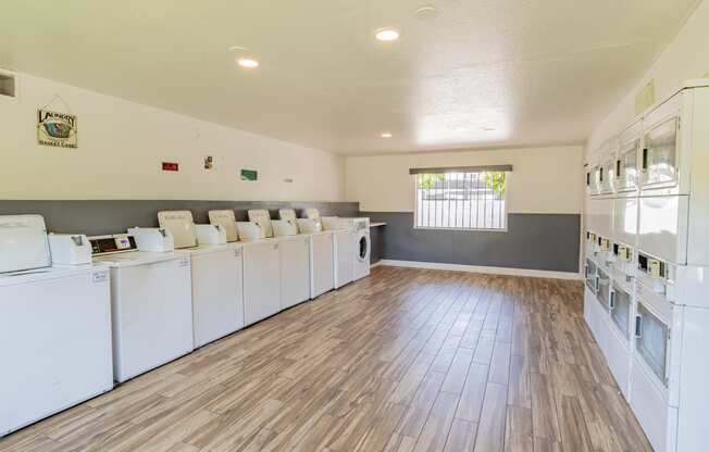 a community laundry room with washers and dryers and a wood floor