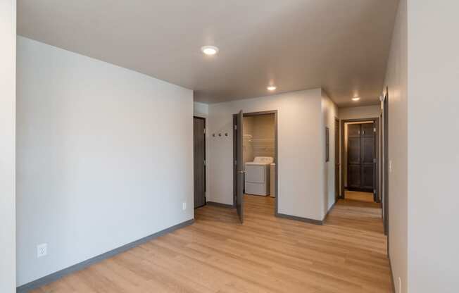 A dining room with white walls and wood flooring with a hallway. Fargo, ND Granger Court Apartments.