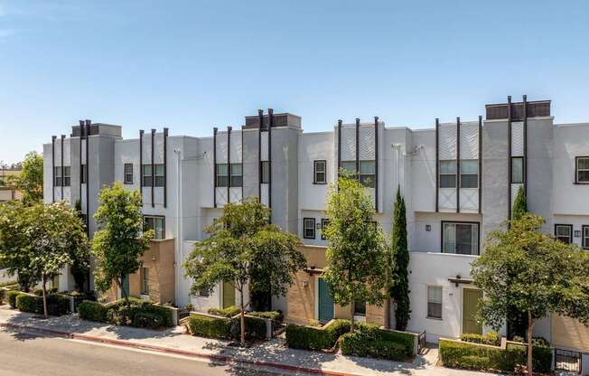 A row of modern townhouses with trees in front.
