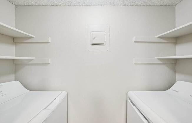 Two white washing machines in a laundry room.